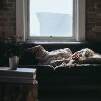 woman lying on her couch in a dark room during the day