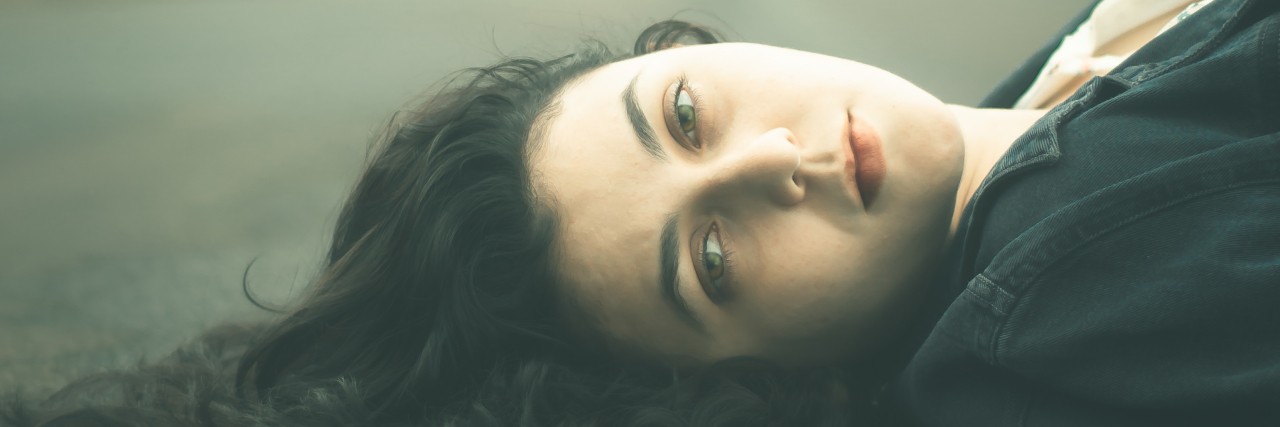 Borderline Personality Disorder and Being Sexually Assaulted by Friend photo of dark haired woman lying in road and looking into camera