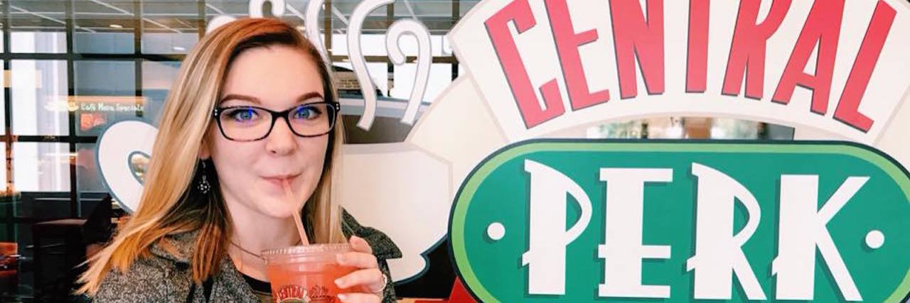 Coping With Fibromyalgia and Anxiety Flare-Ups woman holding a drink and standing in front of central perk sign
