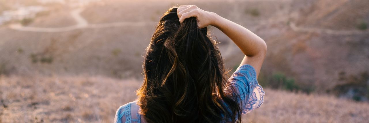 Life Lessons I’ve Learned Through Living With Depression woman looking out over misty valley with hand in hair