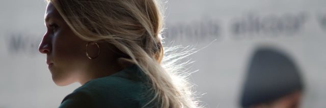 blonde woman looking away, partially hidden in the shadows