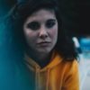close up photo of young woman looking sad wearing yellow hoodie