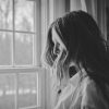 black and white photo of woman looking out of window