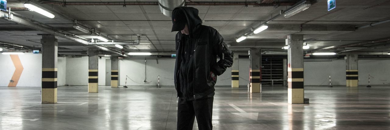 photo of young man standing in car parking garage at night alone