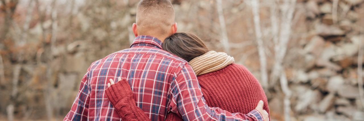 To My Husband: For All He Does to Help With My Mental Health husband and wife cuddle holding each other when sitting by water and trees