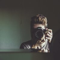 man taking self-portrait in mirror with canon camera