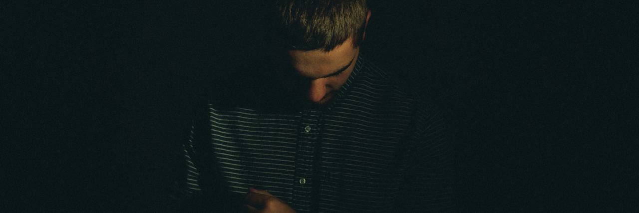 OCD Makes Me Need to Be Seen as a Good Person photo of man standing in darkness looking down