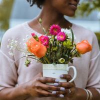 woman holding pot of colorful flowers and smiling