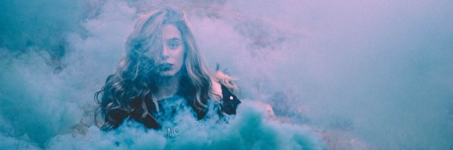 A woman surrounded by blue smoke and fog.