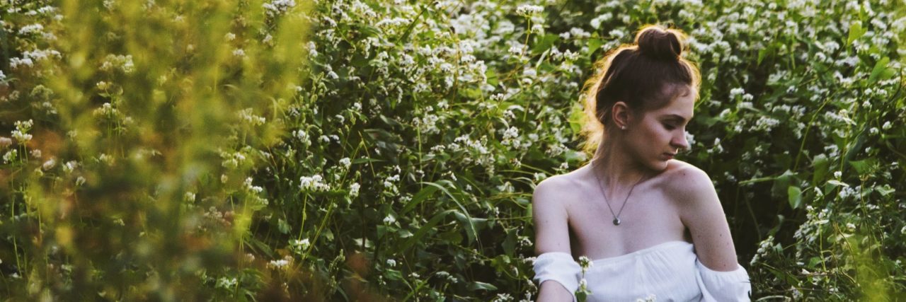 What It's Like to Face Your Loved Ones After Surviving Suicide Attempt young woman sitting in meadow looking upset