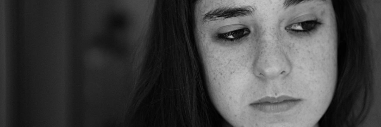 black and white photo of young woman with freckles looking sad