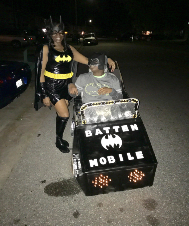mother and son dressed up for halloween in a "bat mobile" for batten disease