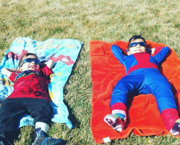 two brothers smiling, laying on the ground