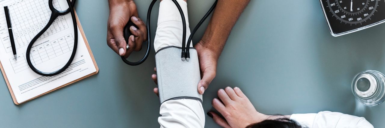 A picture of a doctor checking a woman's blood pressure.