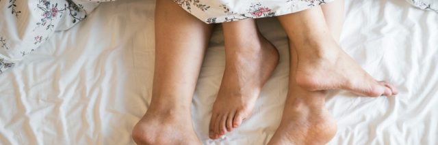 couple feet appearing from below bedsheet cuddled together