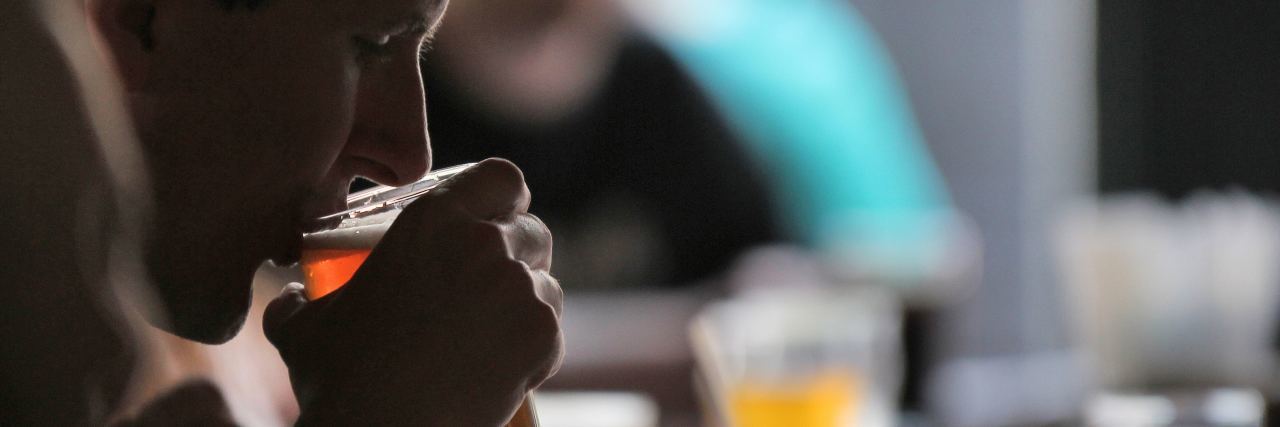 I Thought Drinking Alcohol Made My Stutter Disappear close up photo of man drinking pint of beer