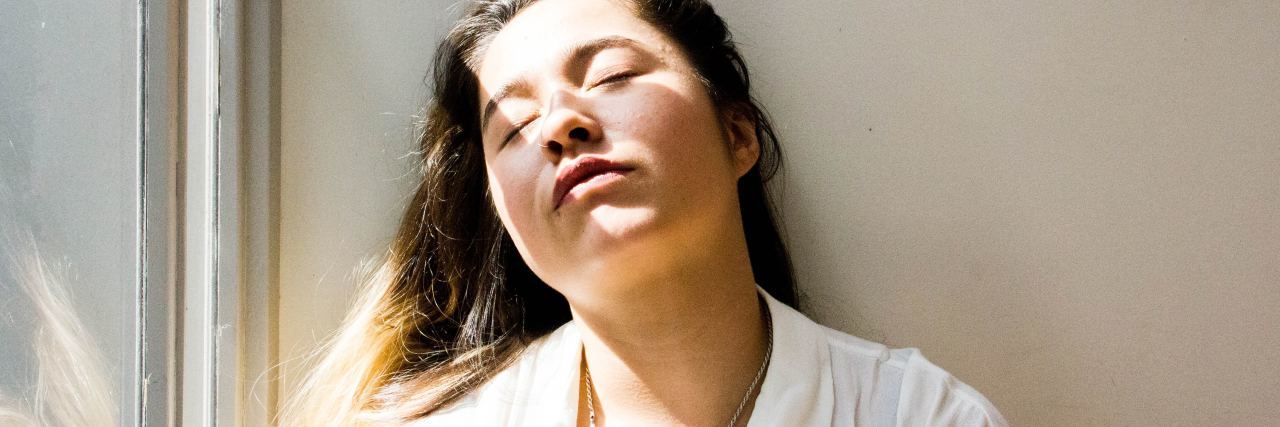 Ulcerative Colitis: When People Say I'm 'Too Young' to Be So Tired woman leaning against a wall with her eyes closed