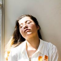 woman leaning against a wall with her eyes closed