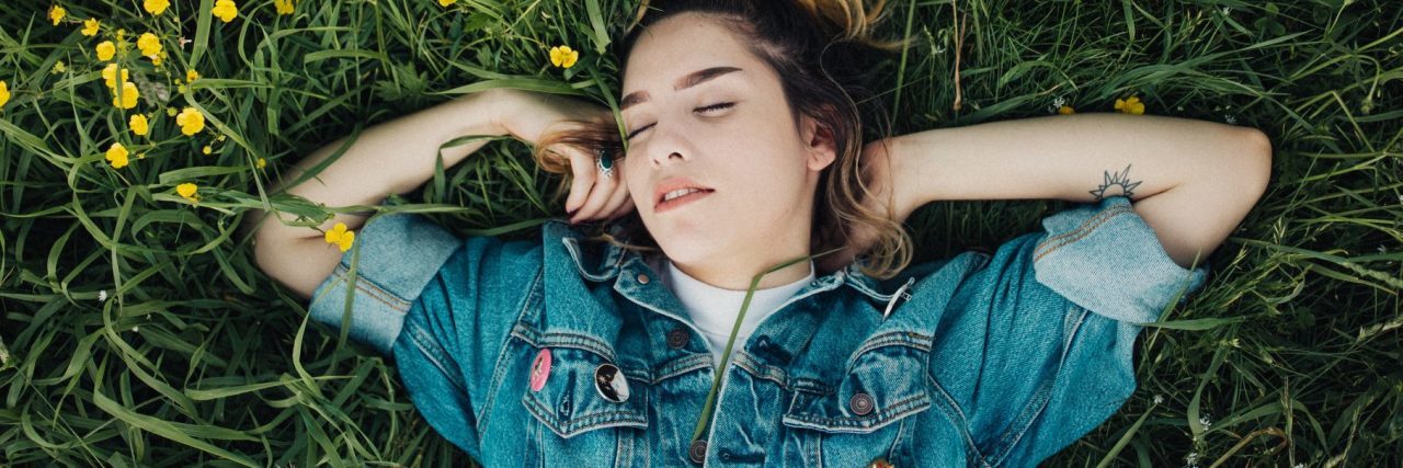 young woman lying on back in wildflower meadow
