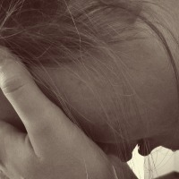 sepia photo close up of woman with head in hands crying