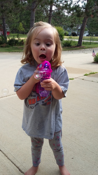 Little girl with Down syndrome marveling at a bubble maker