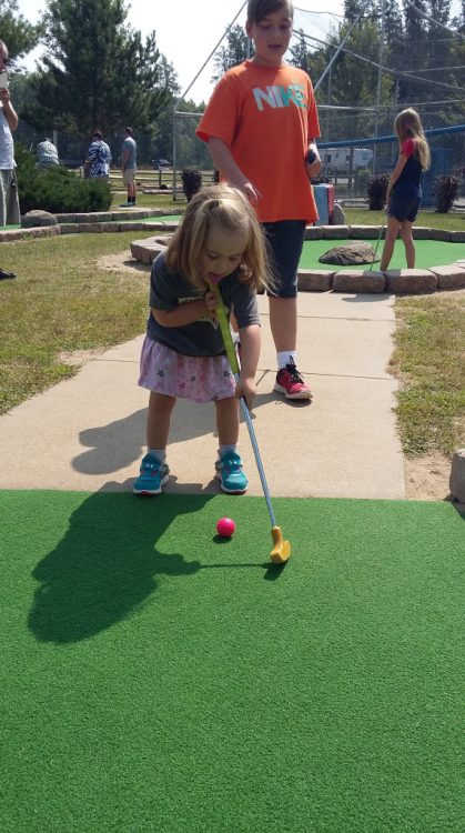 Little girl with own syndrome playing mini golf