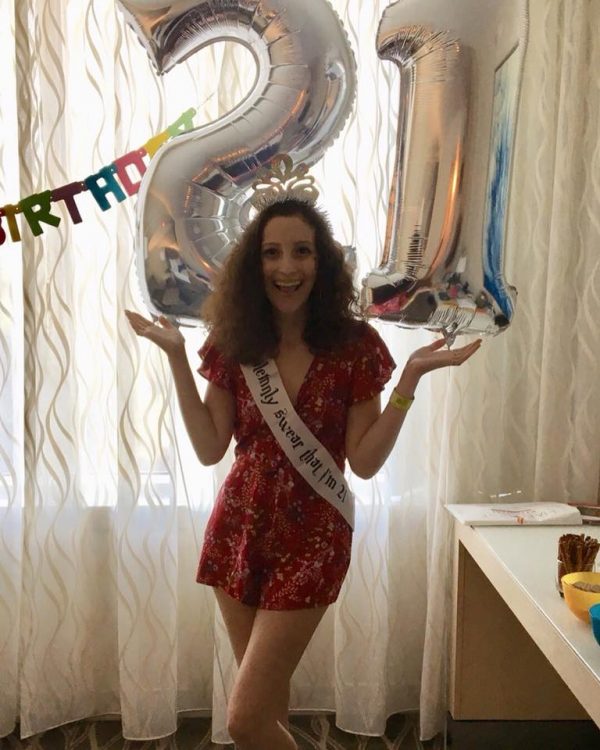 woman standing in front of giant "21" balloons