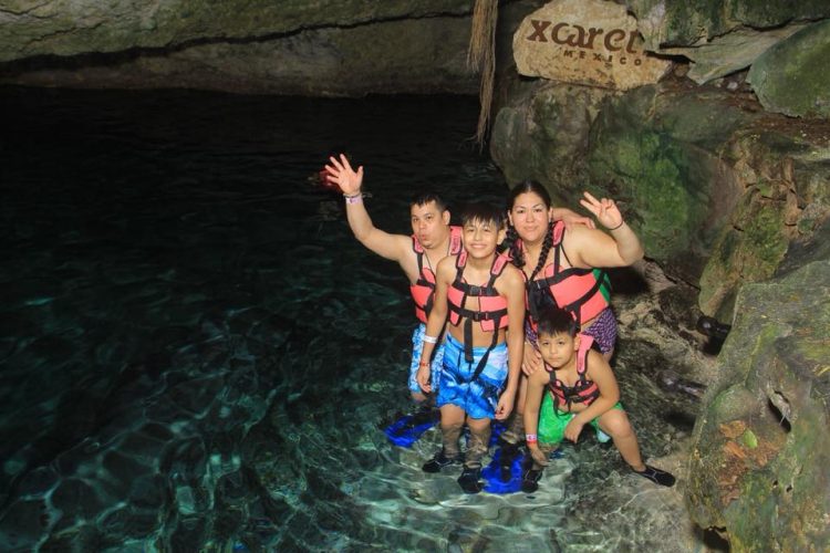 mom and three young boys in water filled cave