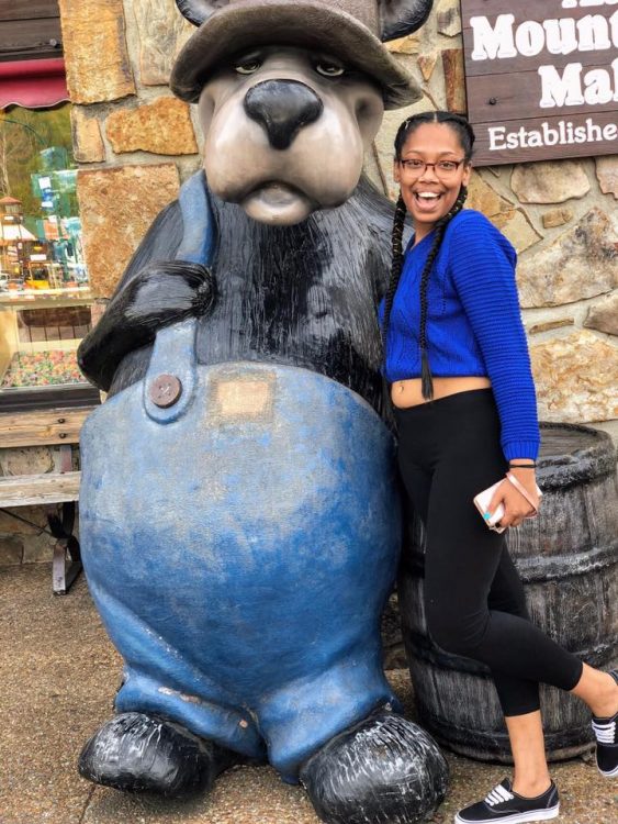 girl posing with bear statue