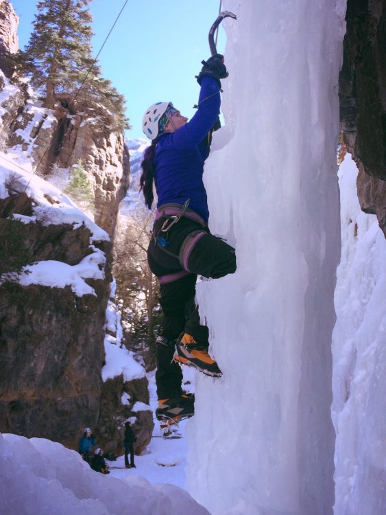 woman climbing up snowy mountain