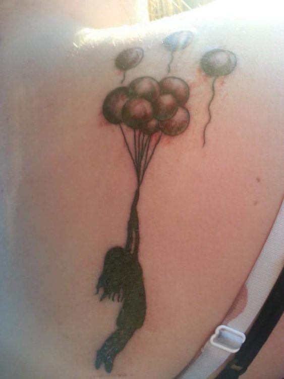 Tattoo of balloons floating upward, with a child holding onto the balloon strings and being lifted with the balloons.