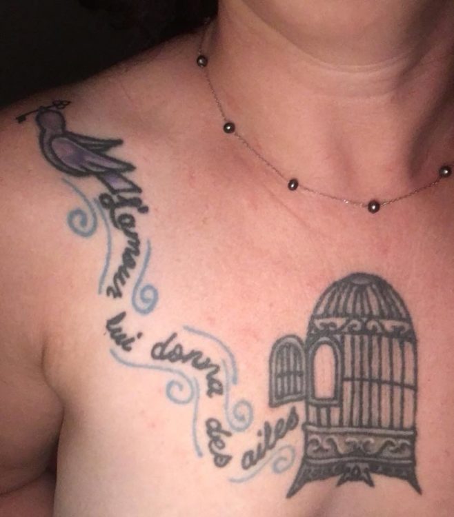 Tattoo of a birdcage over a woman's heart, with the bird flying away.
