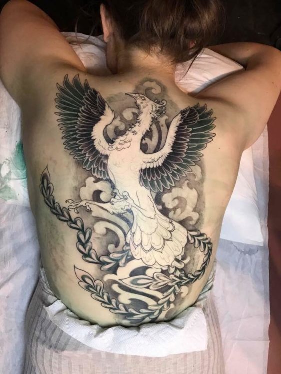 A full back tattoo of a phoenix with wings spread.