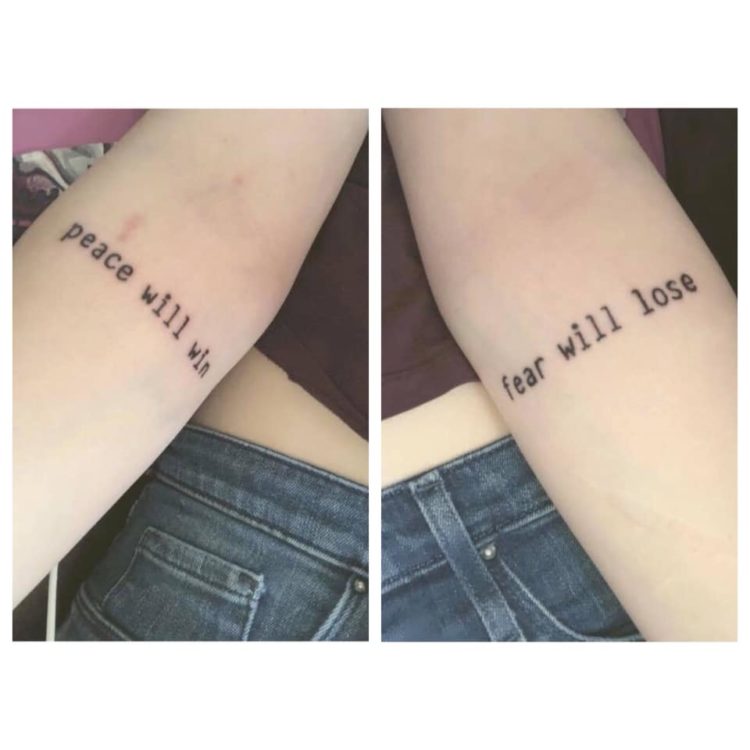 Two arms with tattoos on each. One side has the tattoo "peace will win," while the other side has "fear will lose."