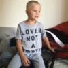 Image of little boy wearing grey shirt that reads: "Lover not a fighter."