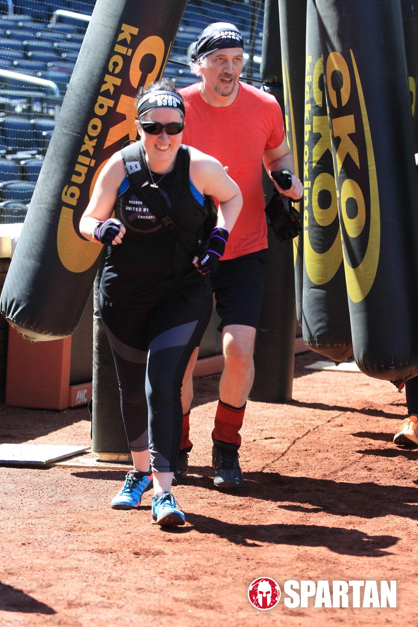 Jess with her sighted guide in a Spartan race. She is running ahead of him.