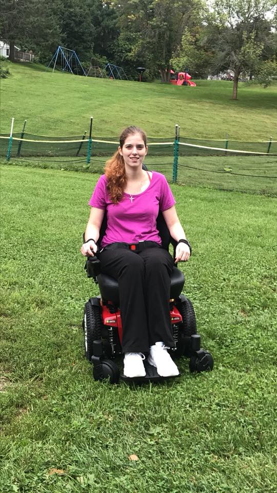 woman sitting in her wheelchair in the middle of a field