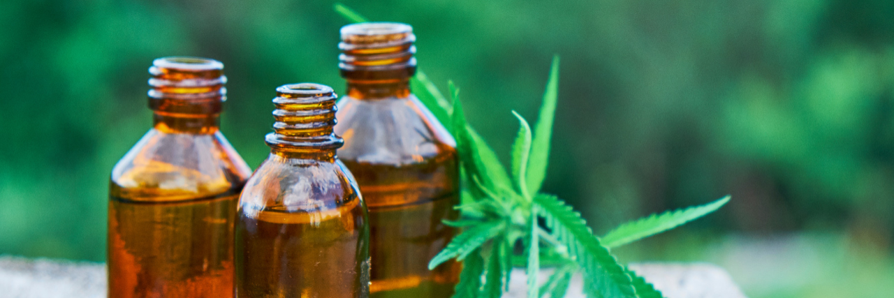 DEA Reclassified CBD-Based Drug, Epidiolex, to Show Lowest Risk for Abuse Three bottles of oil with marijuana leaves next to them.