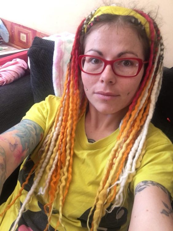 A woman with red glasses, yellow/orange hair