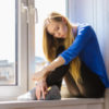A picture of a woman sitting on a windowsill.