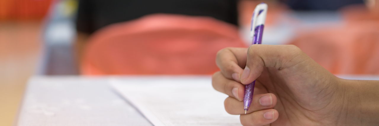 From Disability Living Allowance to Personal Independence Payment Hands with pen over application form.