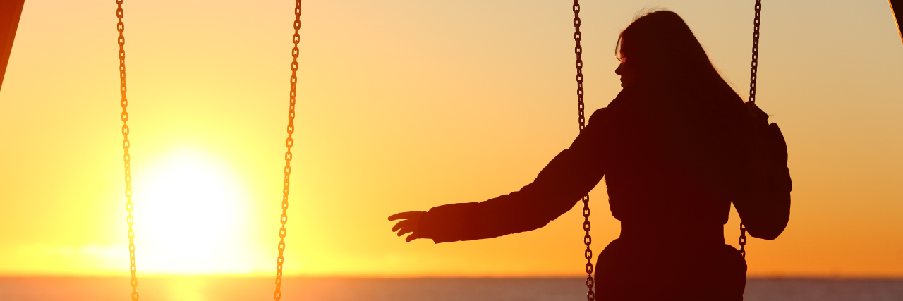 woman on a swing at sunset