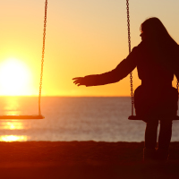 woman on a swing at sunset