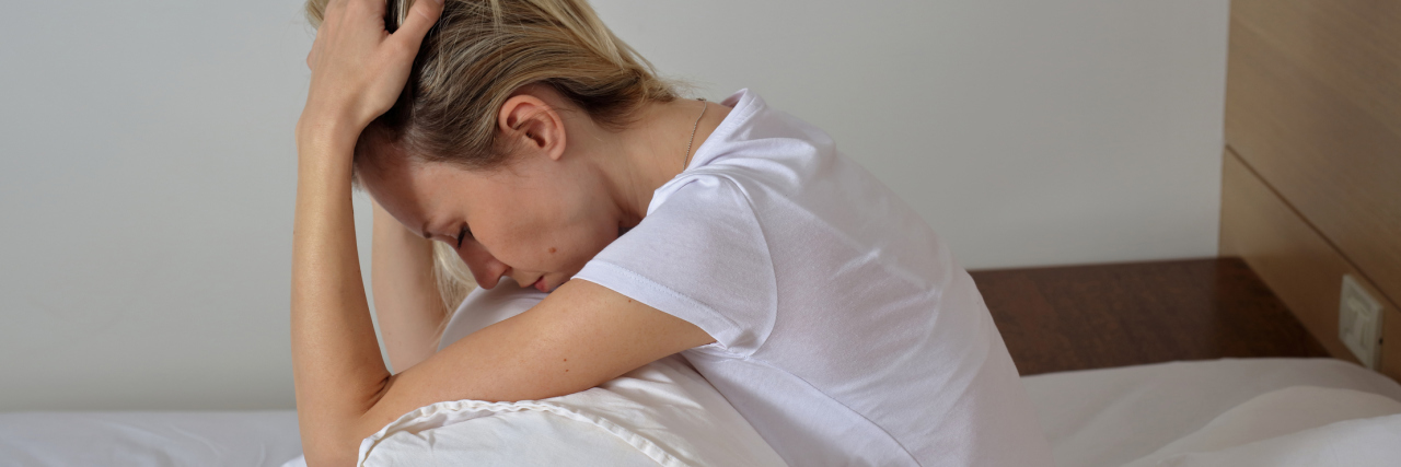 When Illness Keeps You From Enjoying the Summer With Your Children woman sitting in bed with her head in her hands