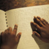 Hands of Black person reading Braille book.