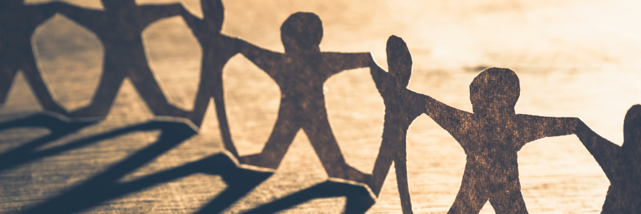 The Importance Of Human Connection When Living With Chronic Pain Human chain paper with light and shadow on wood table
