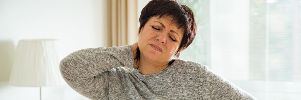 Why It's Too Painful for Me to Keep Explaining My Medical Conditions A picture of a woman holding her neck and back in pain.