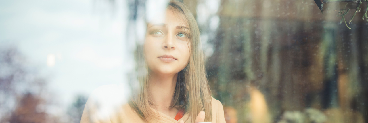 Why I'll Explain My Pain for Pain Awareness Month A picture of a woman sitting alone, looking out a window.
