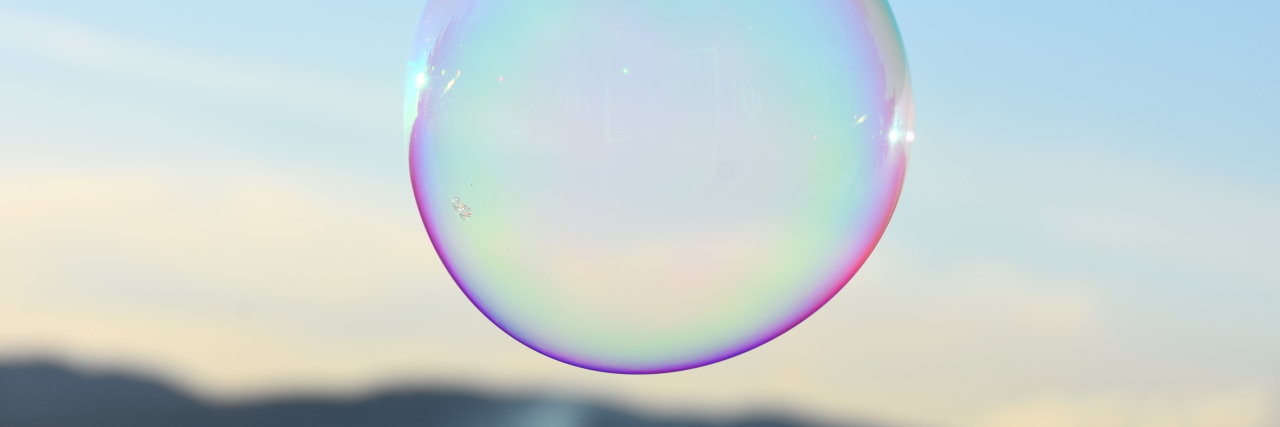 How My Depression Is Like Carrying A Bubble Single bubble with purple outlining floating in a blue sky with a mountain behind it