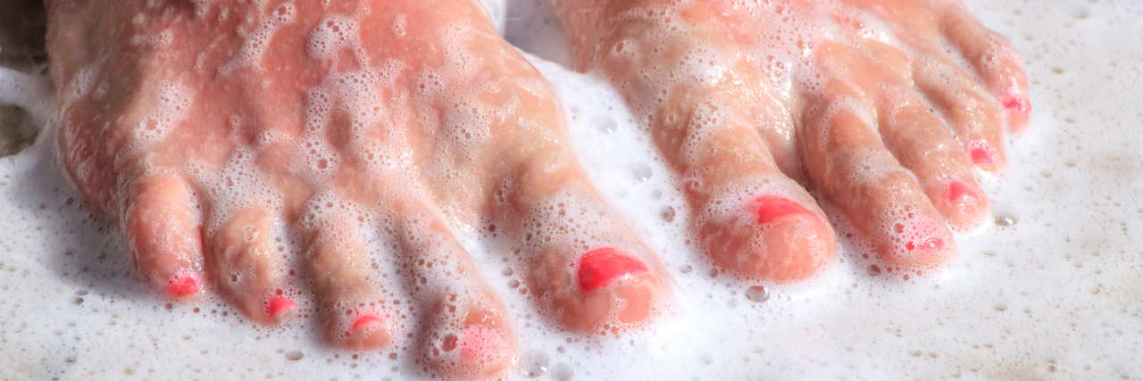 woman's feet standing in soapy water of a shower